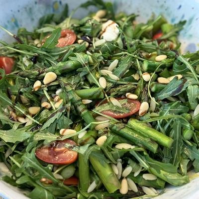 Salat mit Rucola, grünem Spargel, Cocktailtomaten und Pinienkernen