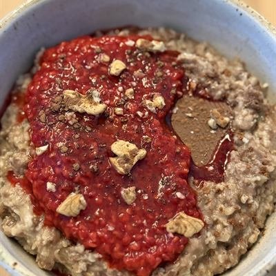 Porridge mit Himbeerpüree, Walnüssen und einem Stück Zartbitterschokolade