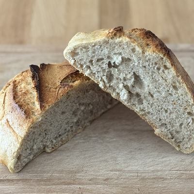 Aufgeschnittenes Sauerteigbrot mit knuspriger Kruste auf einem Holzbrett