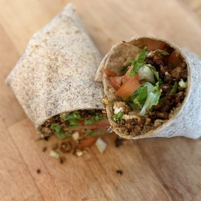 Zwei Hälften eines Tofu-Guacamole-Wraps auf einem Holzbrett